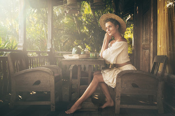 Happy woman sitting on the summer terrace and drinking coffee