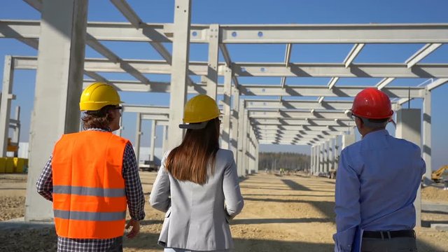 Construction Business Team Walking on Building Site. Business, Building, Teamwork and People Concept. Project Management and Field Crew Meeting on Construction Site.