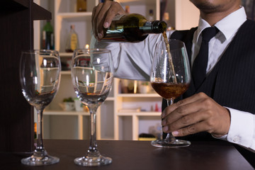 Waiter pouring wine into glasses at the bar.