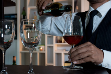 Waiter pouring wine into glasses at the bar.