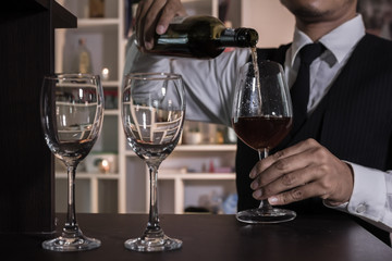 Waiter pouring wine into glasses at the bar.