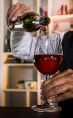 The waitress was pouring a glass of red wine. 