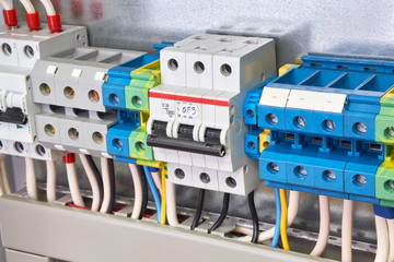 The three-phase circuit breaker is installed in the same row with the connection terminals in the electrical Cabinet. Cables, wires are connected to the switch and terminals. Production, adjustment.