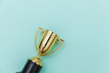 Simply flat lay design winner or champion gold trophy cup isolated on blue pastel colorful...