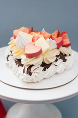 Heart shaped pavlova cake with melted dark chocolate, hearts, strawberry and cream cheese. 