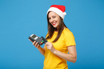 Smiling Santa girl in Christmas hat posing isolated on blue background. New Year 2020 celebration...