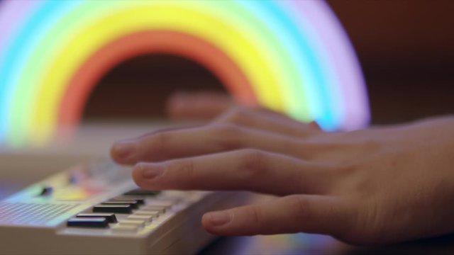 Soft focus side view of kids hands playing a small keyboard