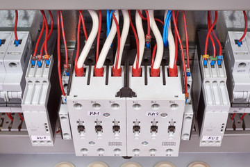 Electrical cables and wires are connected from the top to the contactors or starters and relays of...