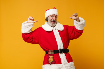 Fototapeta na wymiar Cheerful elderly gray-haired mustache bearded Santa man in Christmas hat isolated on yellow background. Happy New Year 2020 celebration holiday concept. Mock up copy space. Pointing thumbs on himself.