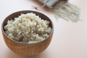Cooked quinoa in wooden bowl  on  brown background