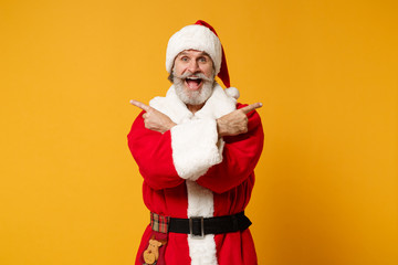 Fototapeta na wymiar Elderly gray-haired bearded mustache Santa man in Christmas hat posing isolated on yellow background. New Year 2020 celebration concept. Mock up copy space. Pointing fingers aside, hold hands crossed.
