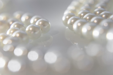 A necklace of pearls lying on white glass