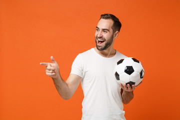 Cheerful young man in casual white t-shirt posing isolated on orange background in studio. People...