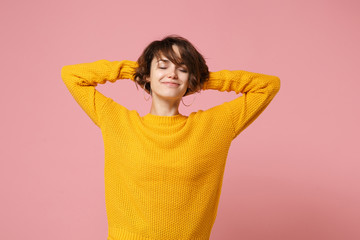 Relaxed young brunette woman girl in yellow sweater posing isolated on pastel pink wall background,...