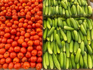 Big pile of red tomatoes and fresh cucumbers at hypermarket