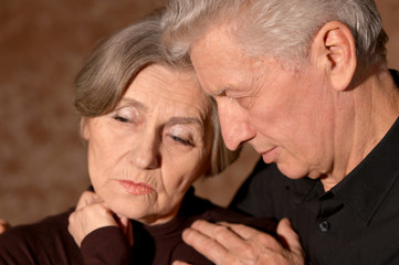 Close up portrait of sad senior couple posing at home