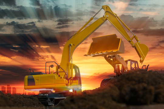 Excavators and wheel loader are digging the soil in the construction site on the sunset background