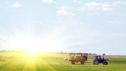 Tractor loading hay bales on truck agricultural works