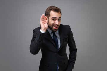 Confused young bearded business man in classic suit shirt tie posing isolated on grey background....