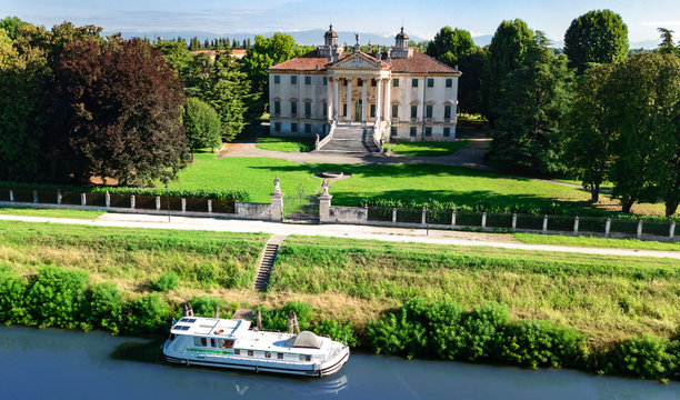 Aerial top view of ancient villa Giovanelli, garden and houseboat barge on canal Brenta from above, family vacation cruise on boat, Padua (Padova) in Veneto, Venice region, Northern Italy