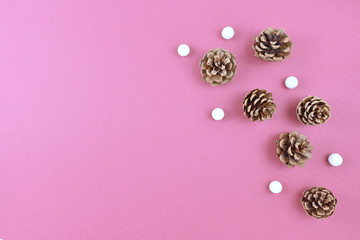 Seasonal Christmas flat lay with fir cones and gittering small white snowballs on right side and empty copy space on left side on light pink background 