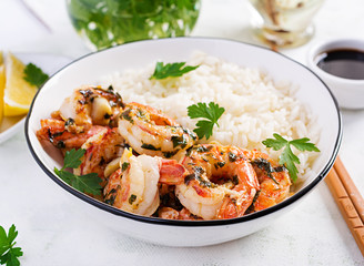 Grilled shrimps and boiled rice. King prawn tails in orange-garlic sauce with parsley.