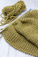 Fototapeta na wymiar Knitting jumper with merino wool yarn and with a knit stitch. On a grey wood surface