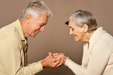 Close up shot of a cheerful senior couple at home holding hands