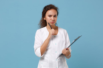 Puzzled african american female doctor woman in white medical gown hold clipboard with medical document isolated on blue background. Healthcare personnel medicine health concept. Mock up copy space.