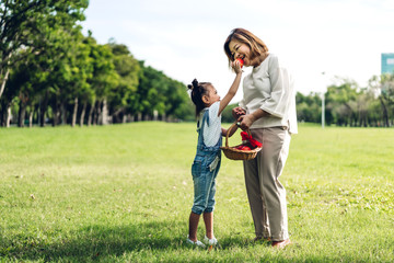 Portrait of happy grandmother and little cute girl enjoy relax together in summer park.Family and togetherness