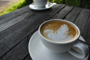 Close up a white coffee cup with heart shape on wood desk