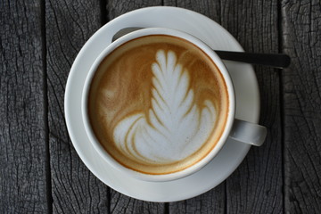 Close up a white coffee cup with heart shape on wood desk