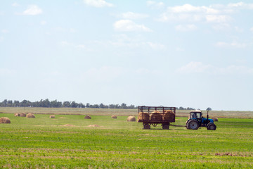 Obraz premium Tractor loading hay bales on truck agricultural works