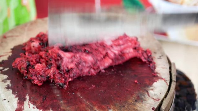 Selective focus of minced raw pork being chopped and prepared on a wooden board for making a traditional northern Thai pork salad, blood, bile and herbs ( Laab dib )