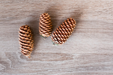 Fir cones lie on a wooden background.