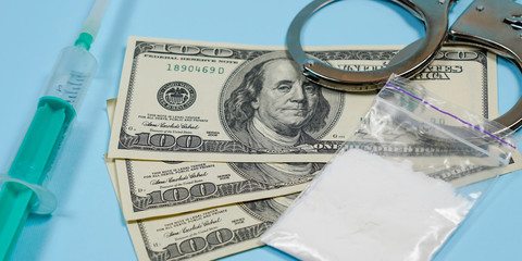 A bag of drugs, US dollars and handcuffs on the table.