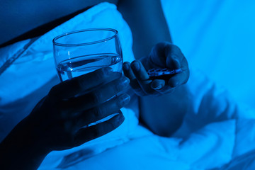 Female hands with a glass of water and sleeping pills