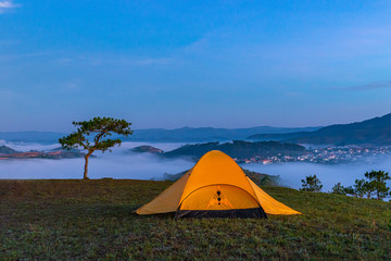 Yellow tent camping on hill under misty weather at dawn 