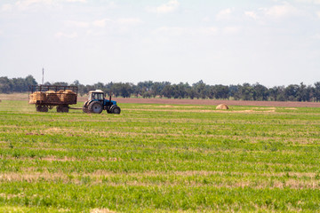 Tractor loading hay bales on truck agricultural works