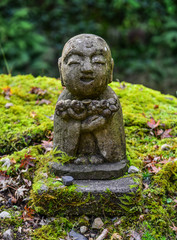 Fototapeta na wymiar Stone statue of smiling Jizo Bosatsu