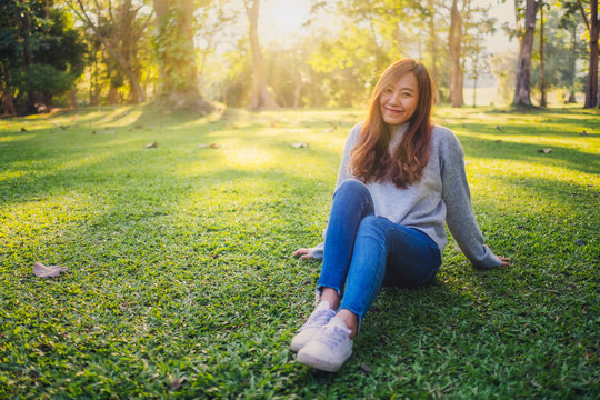 Portrait image of a beautiful asian woman sitting among nature in the park before sunset