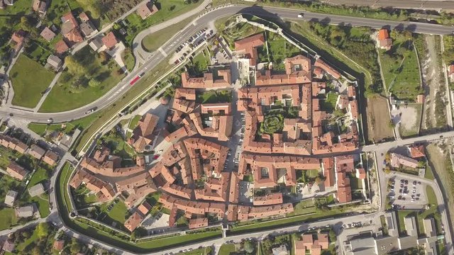 Top down aerial view of a small historic town Venzone in Northern Italy with red tiled roofs of old buildings.