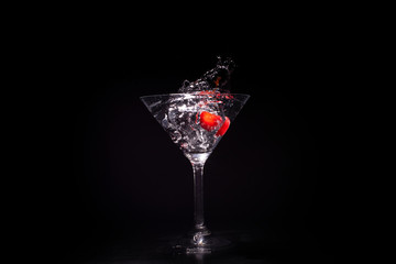 Red apple splashing in glass against black background