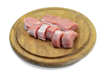 Fresh raw beef meat slices on a round wooden board isolated over white background