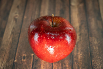A shiny red apple on a wooden table