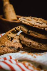 Chocolate chip cookies on white napkin on wooden table. Stacked chocolate chip cookies close up.