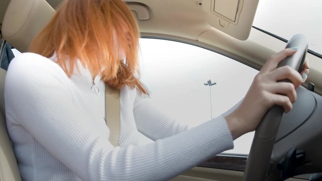 Pissed off displeased angry aggressive woman driving a car shouting at someone with hand fist up.