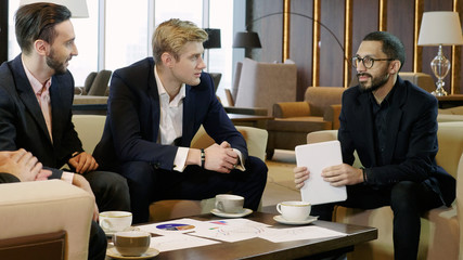 Four businessmen discussing a deal at business meeting in modern restaurant