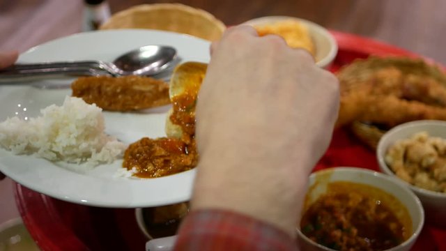 Northern Thai style dinner, Khantok dinner, which the food being scooped and put on a plate of a tourist