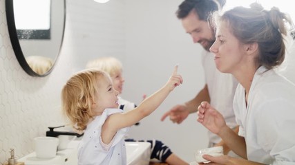 Young family with two small children indoors in bathroom, having fun. - Powered by Adobe